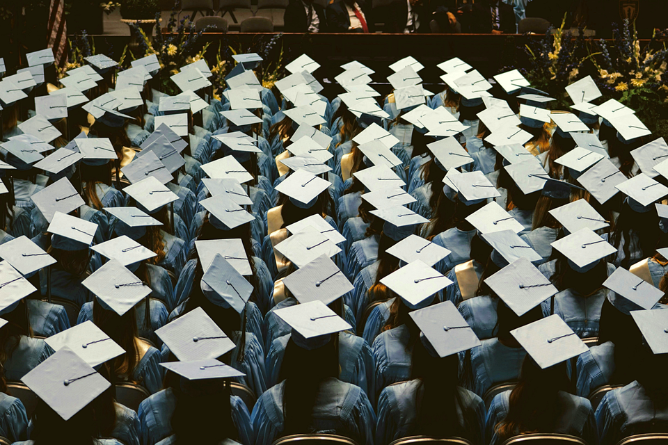 A rear-shot colour photo of seated university students at their graduation ceremony. Photo by Joshua Hoehne from Unsplash.